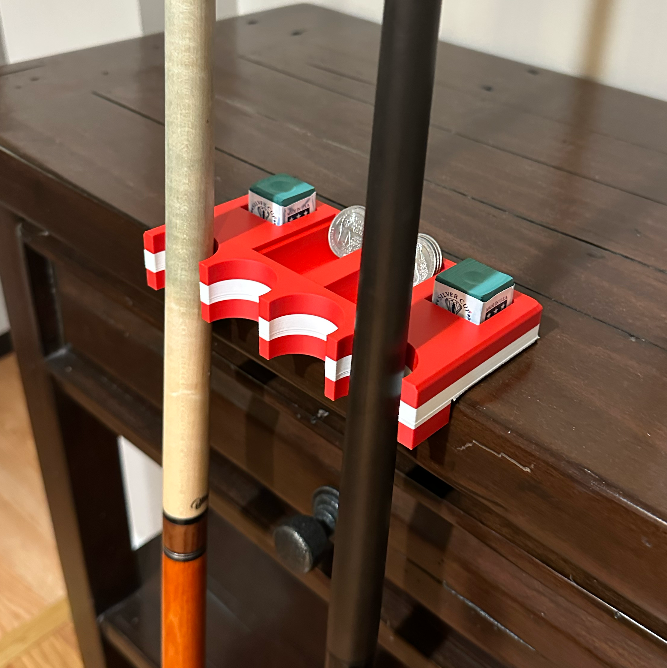 Canadian flag cuezy cue holder with coins and chalk on a table with two pool cues